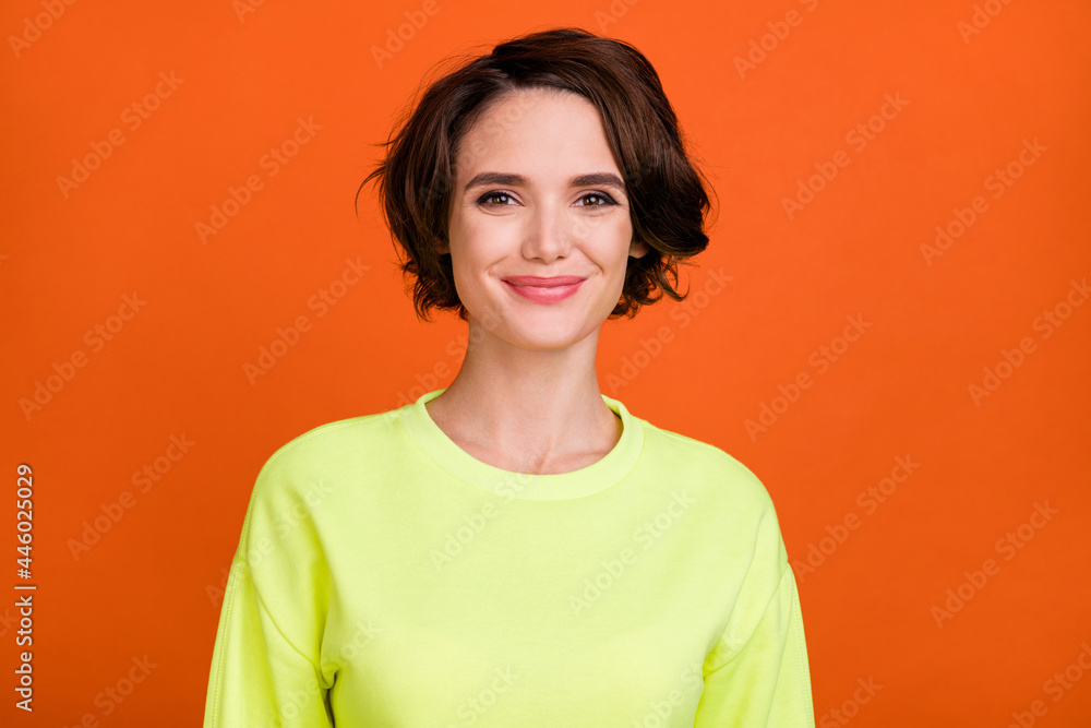 Photo of pretty young positive woman smile good mood wear yellow sweatshirt isolated on orange color background Photo of pretty young positive woman smile good mood wear yellow sweatshirt isolated on orange color background