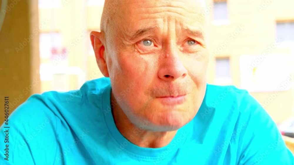 elderly positive man in a blue t-shirt close-up sits in street cafe in the summer, waiting for his order, bright light of the sun concept of vacation, tourist travel, summer vacation, summermood elderly positive man in a blue t-shirt close-up sits in street cafe in the summer, waiting for his order, bright light of the sun concept of vacation, tourist travel, summer vacation, summermood