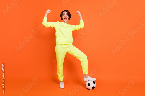 Fototapeta Naklejka Na Ścianę i Meble -  Full length body size view of attractive lucky cheerful girl playing soccer rejoicing isolated over bright orange color background