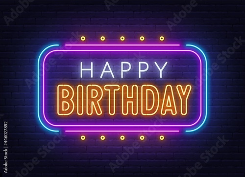 Happy birthday neon sign. Greeting card on brick wall background.