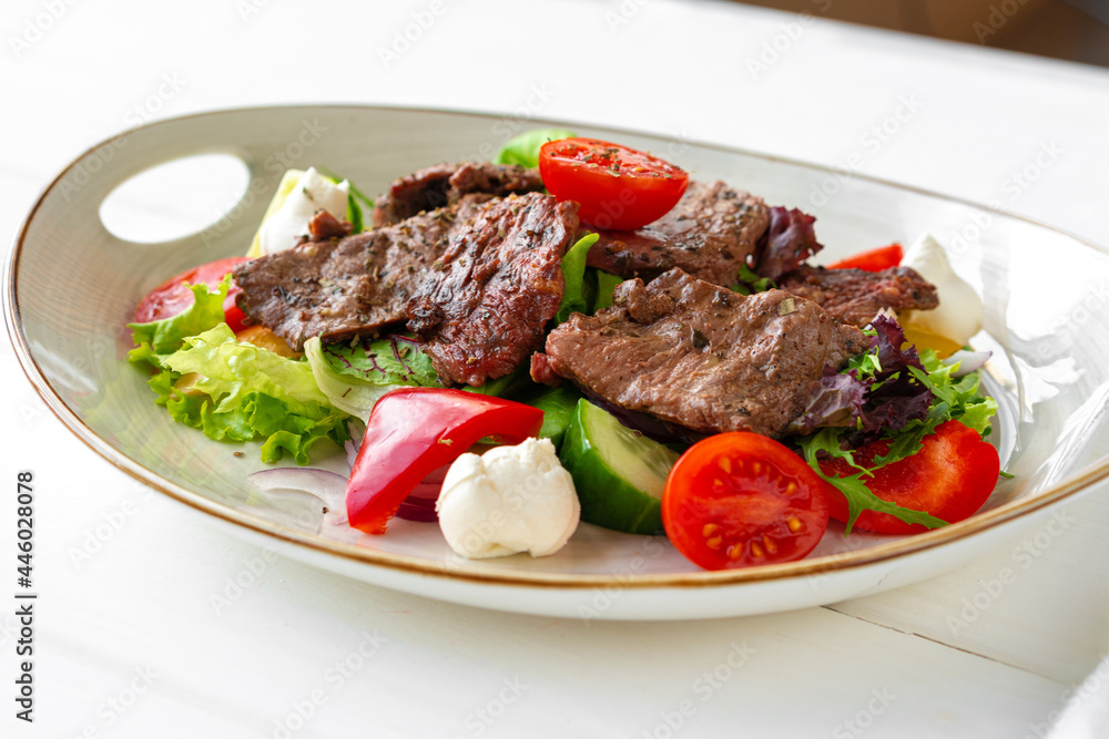 Fillet of beef with vegetable salad on wooden table Fillet of beef with vegetable salad on wooden table