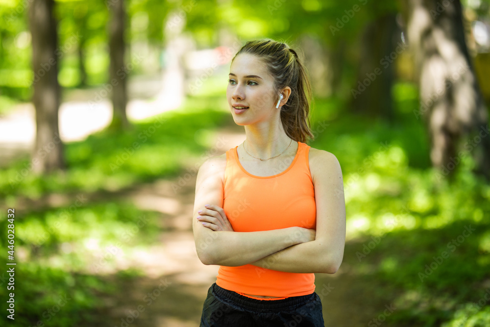 Young sportswoman using earphones doing exercise at the park Young sportswoman using earphones doing exercise at the park