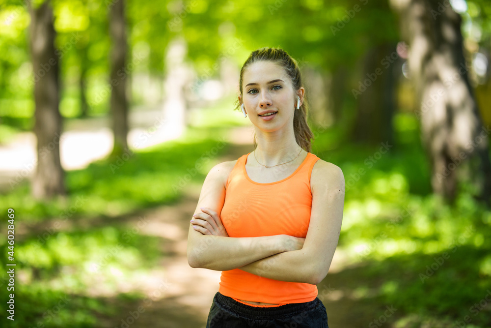Young sportswoman using earphones doing exercise at the park Young sportswoman using earphones doing exercise at the park