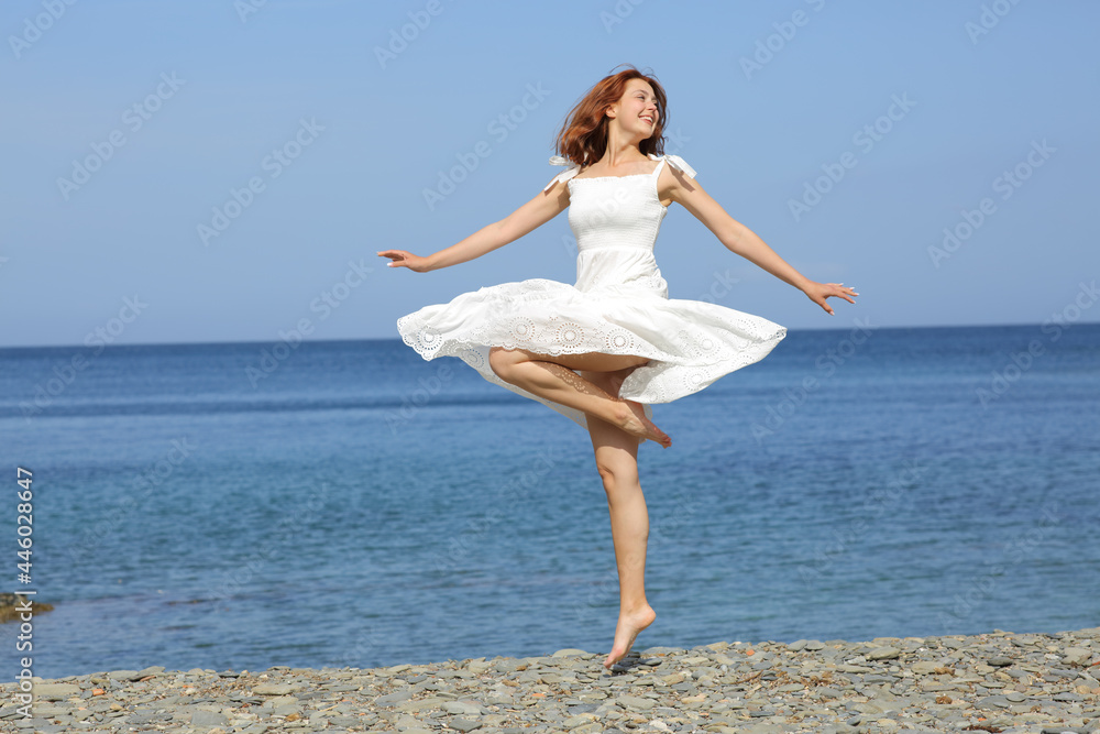 Happy woman wearing dress twirling on the beach Happy woman wearing dress twirling on the beach