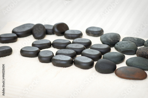 Many black massage stones lying isolated on the towel on the table