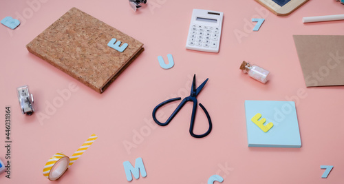 Back to school creative concept. Colorful pattern of vibrant foam letters, scissors, calculator and other stationery in a chaotic manner lying on pink paper background. Flat lay.