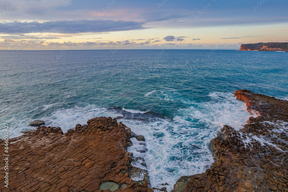 Aerial sunrise seascape with clouds and rock platform