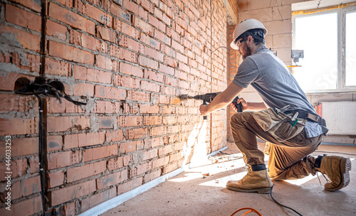 The builder works with a drill in working form. photo