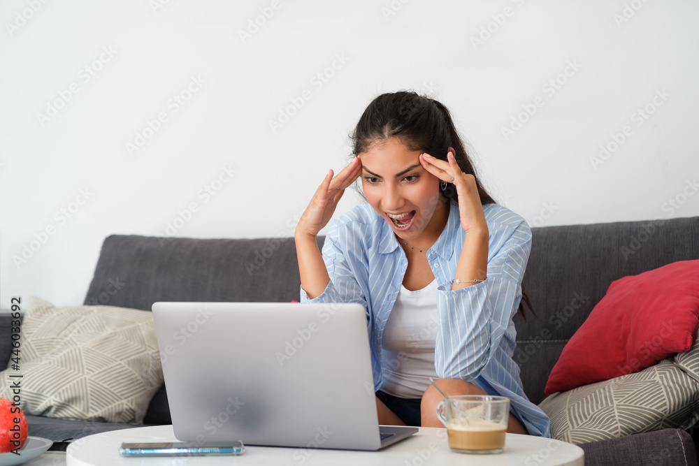 Funny amazed casual latin woman at home looking to her laptop and jawdropping. Funny amazed casual latin woman at home looking to her laptop and jawdropping.