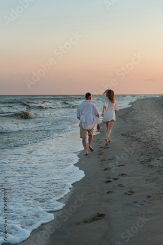 happy beautiful couple walking at sunset along the seashore