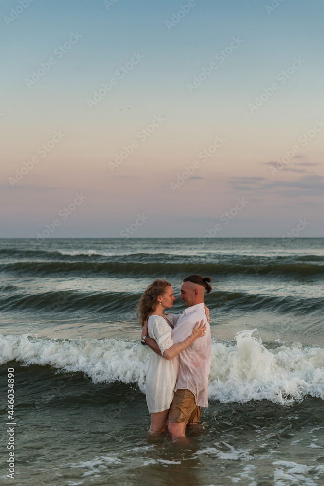 happy beautiful couple walking at sunset along the seashore happy beautiful couple walking at sunset along the seashore