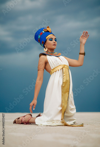 Quadro su tela Woman in image of egyptian queen Nefertiti kneels in desert with closed eyes