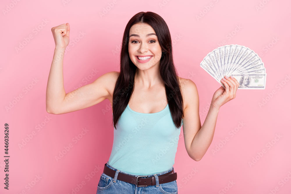 Photo of astonished millennial lady hold money hand fist wear blue top isolated on pink color background Photo of astonished millennial lady hold money hand fist wear blue top isolated on pink color background