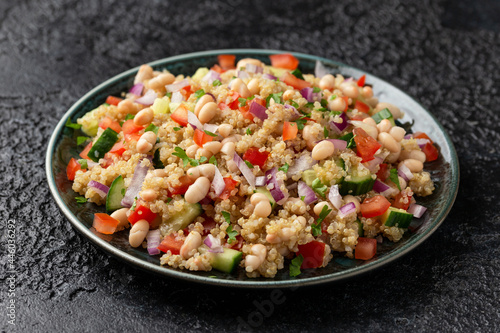 Quinoa white bean salad with cherry tomatoes, cucumber, red onion and herbs. Healthy vegan food © grinchh