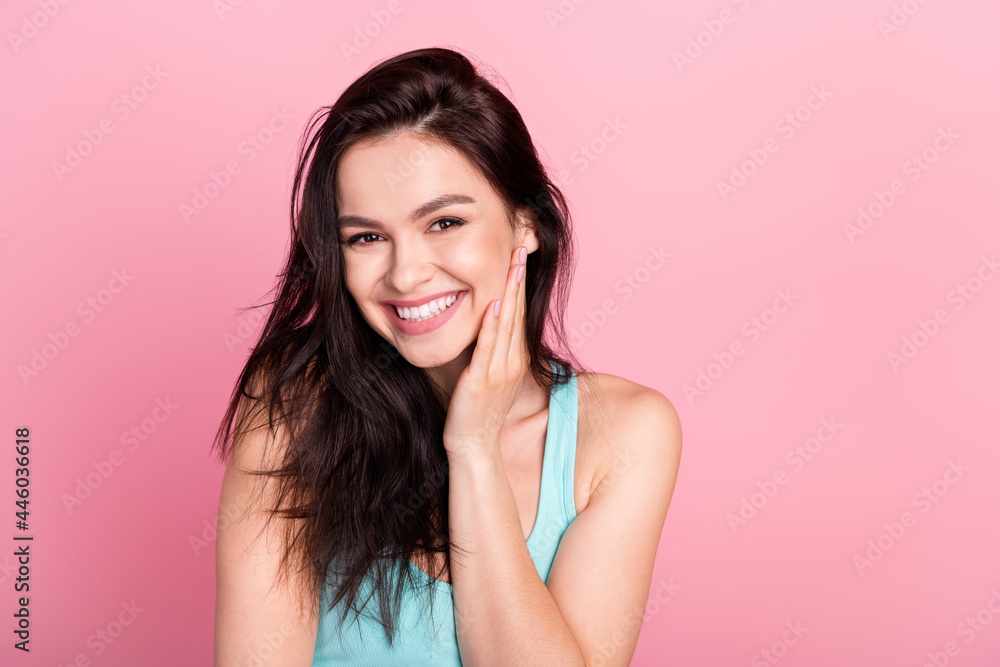 Photo of cute beauty lady touch face wear blue top isolated on pink color background Photo of cute beauty lady touch face wear blue top isolated on pink color background