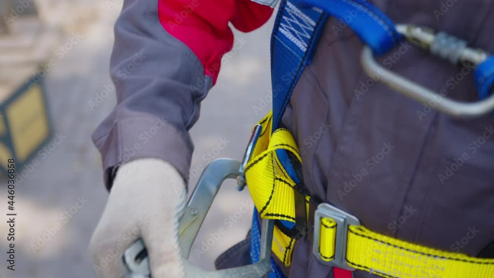 Industrial climber puts on equipment for high-altitude work. On climber s belt carabiners. Industrial climber puts on equipment for high-altitude work. On climber s belt carabiners.