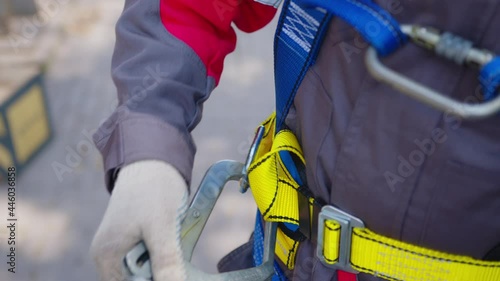 Industrial climber puts on equipment for high-altitude work. On climber s belt carabiners. photo