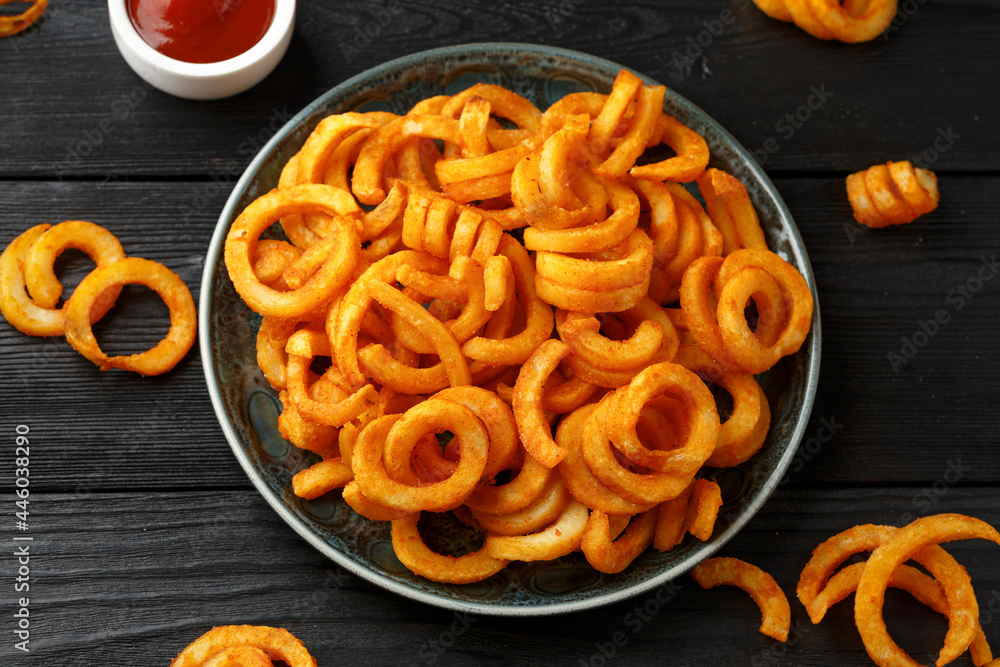 Golden Curly Fries with ketchup on rustic plate Golden Curly Fries with ketchup on rustic plate