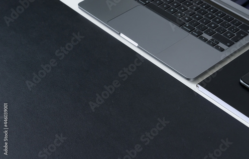 Clean modern workspace with laptop, notebook and matte black work surface on white desk