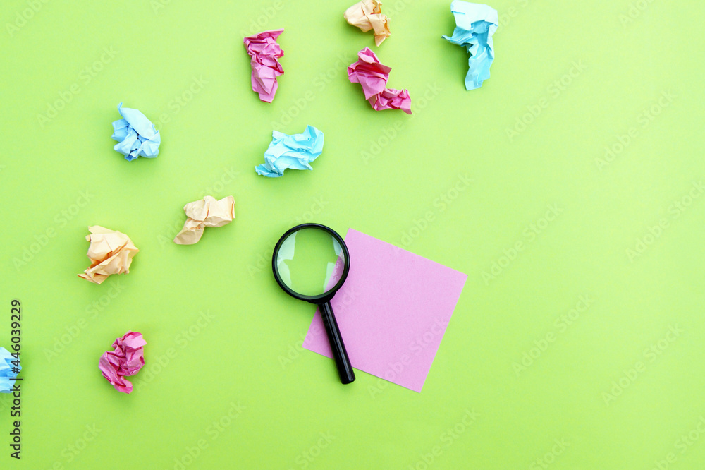 Top view photo of a magnifying glass and blank sticker on a green background. Top view photo of a magnifying glass and blank sticker on a green background.