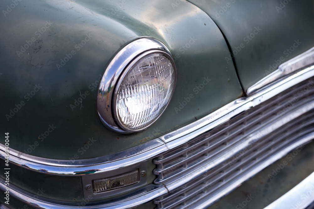 Chrome plated front lamp of a restored classic car. Photo taken in natural light.