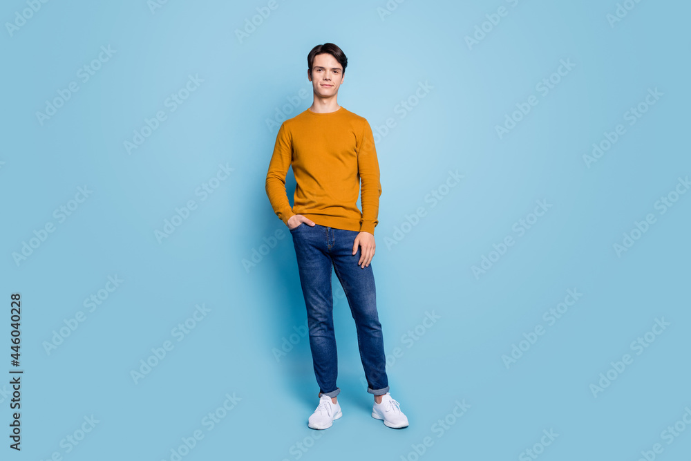Photo of handsome stylish guy posing hand pocket wear orange shirt jeans sneakers isolated blue color background Photo of handsome stylish guy posing hand pocket wear orange shirt jeans sneakers isolated blue color background