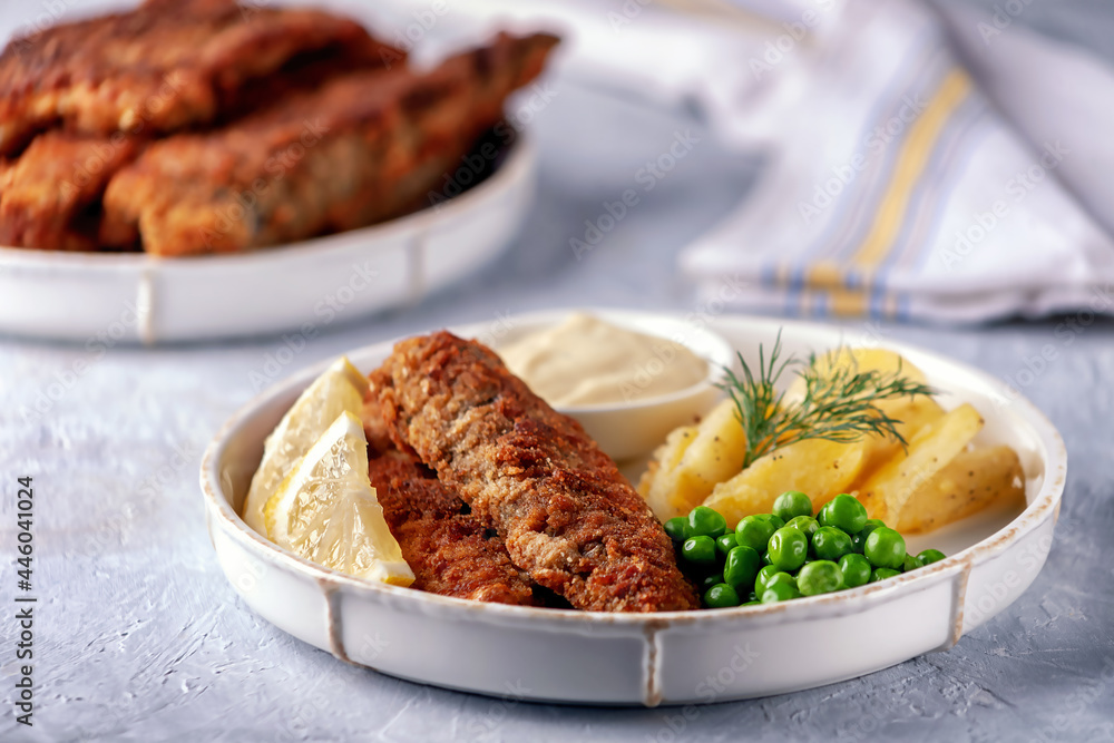 Fried fish with fried potatoes, green peas and lemon Fried fish with fried potatoes, green peas and lemon