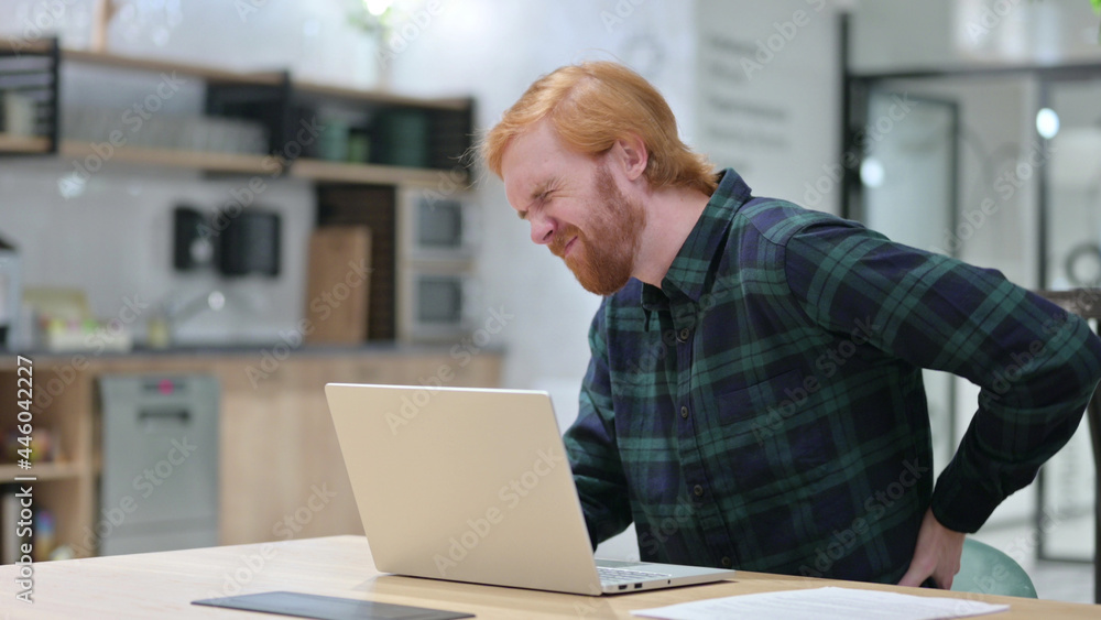 Redhead Man with Back Pain using Laptop in Cafe Redhead Man with Back Pain using Laptop in Cafe