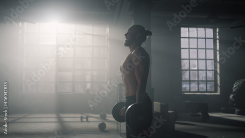 Sportsman breathing heavy before strength exercise. Man lifting weights in gym