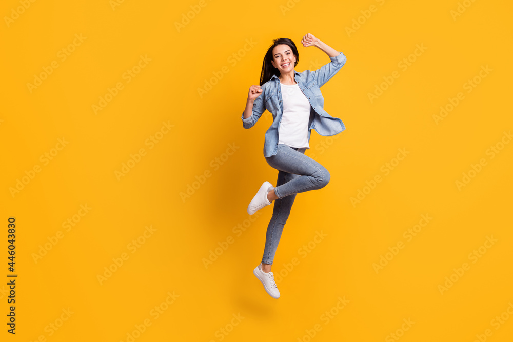 Full size profile photo of cool hooray brunette lady run jump wear blue shirt jeans sneakers isolated on yellow background