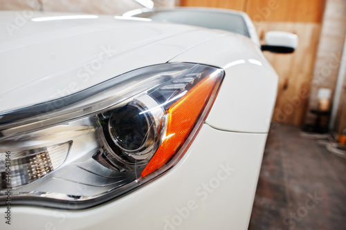 Headlight of white new luxury sport car in detailing garage. © AS Photo Family