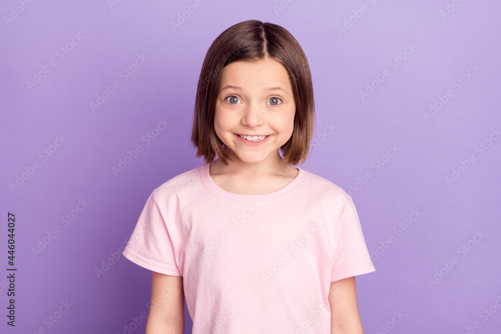 Portrait of attractive cheerful preteen girl wearing pink tshirt isolated over purple violet lilac color background Portrait of attractive cheerful preteen girl wearing pink tshirt isolated over purple violet lilac color background