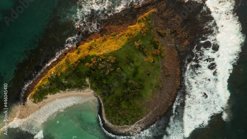 Top down aerial hyperlapse view of Green Island at sunrise with waves hitting the rocks and white sand beach photo