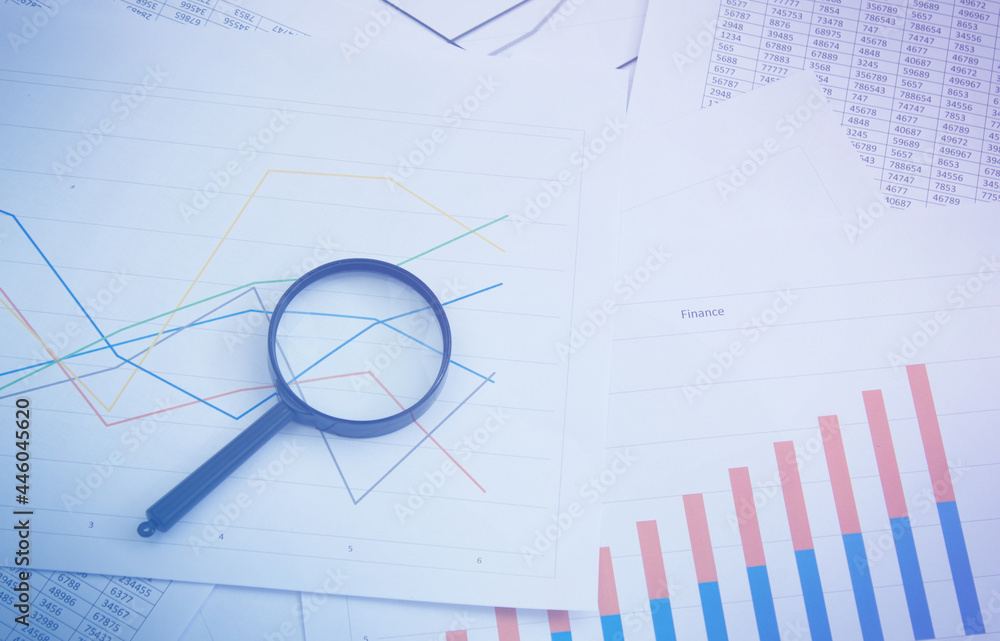 Magnifying glass on charts, graphs and financial statements. Inventory chart analysis and financial accounting. Copy space. Can be used for presentations Magnifying glass on charts, graphs and financial statements. Inventory chart analysis and financial accounting. Copy space. Can be used for presentations