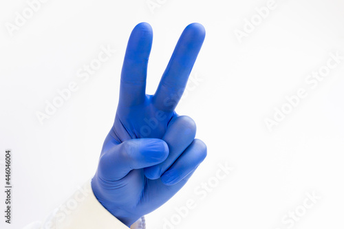 Hand in blue latex Glove raising two fingers up on hand it is shows peace strength fight or victory symbol