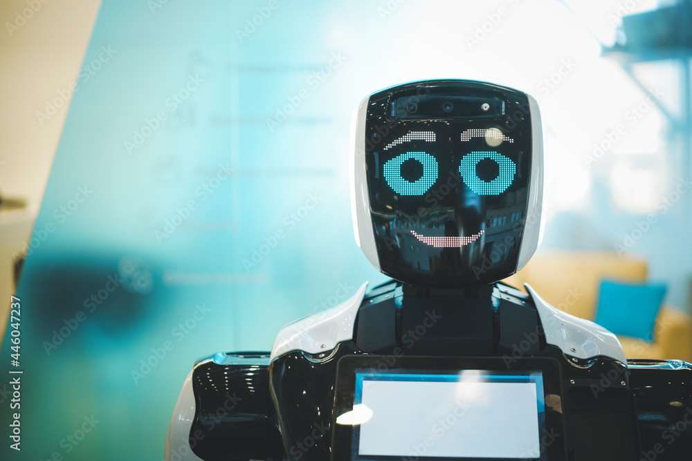 Technological progress of smiling robot assistant with artificial intelligence in public place. Futuristic concept of robotics, machines in daily life Technological progress of smiling robot assistant with artificial intelligence in public place. Futuristic concept of robotics, machines in daily life