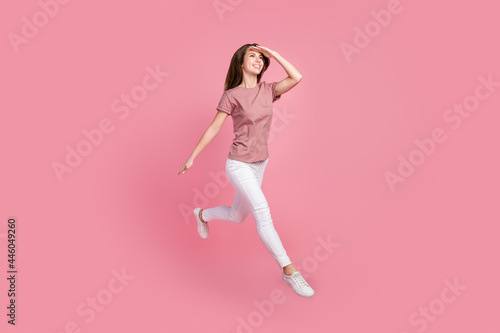 Full body photo of cool brunette millennial lady jump look wear t-shirt jeans isolated on pink color background