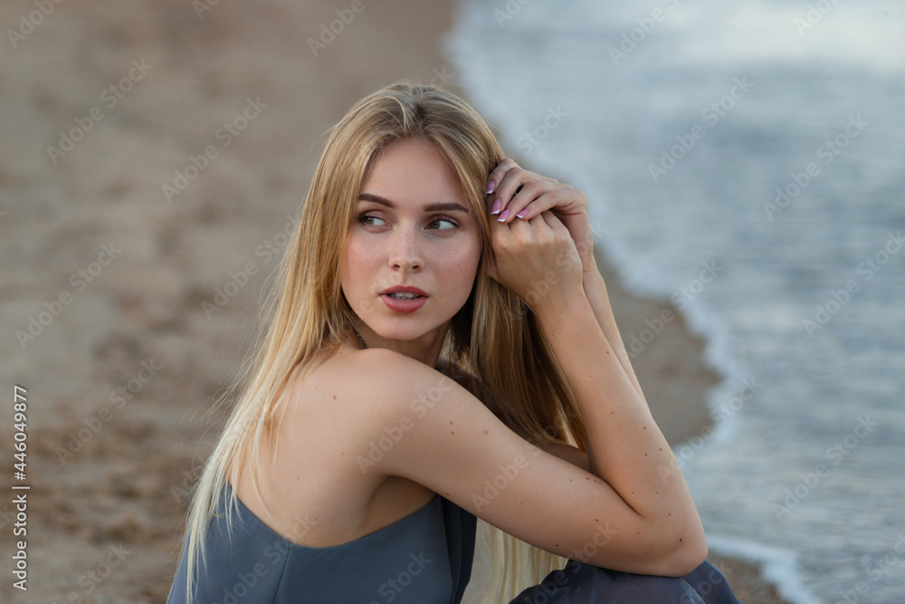 beautiful girl in a gray dress by the sea at sunset