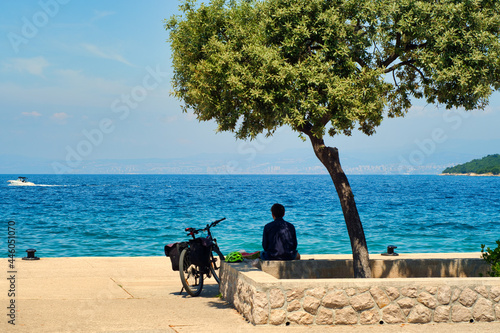 Fototapeta Naklejka Na Ścianę i Meble -  Sweet summer vacation dreams - lonely young man with bike watching the sea on Croatia island Krk