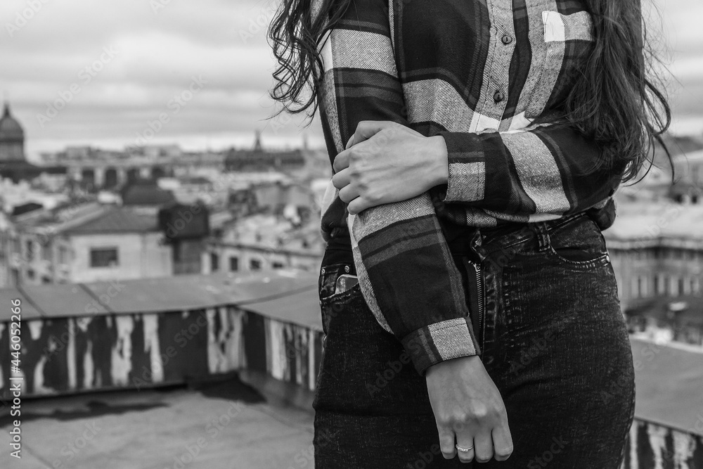 Hands of a girl in a plaid shirt on the background of city roofs