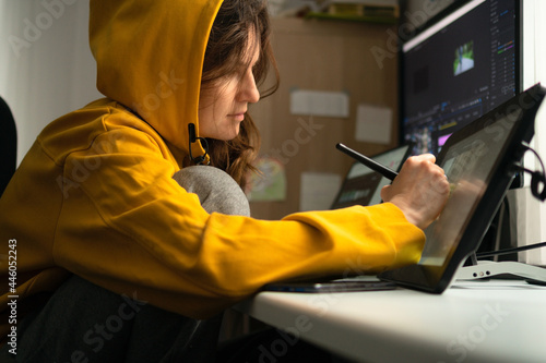 A young female student sitting at the table, using graphics tablet. Woman working from home. Concept for distance learning or home office.