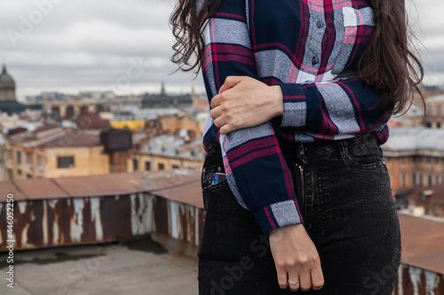 Hands of a girl in a plaid shirt on the background of city roofs
