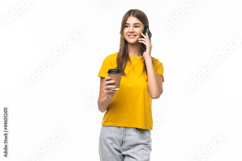 Photo of woman standing with smartphone and takeaway coffee in hands isolated over gray background