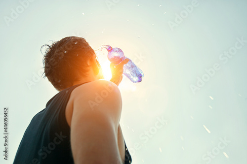 Man pouring water from plastic bottle on his head in hot day photo