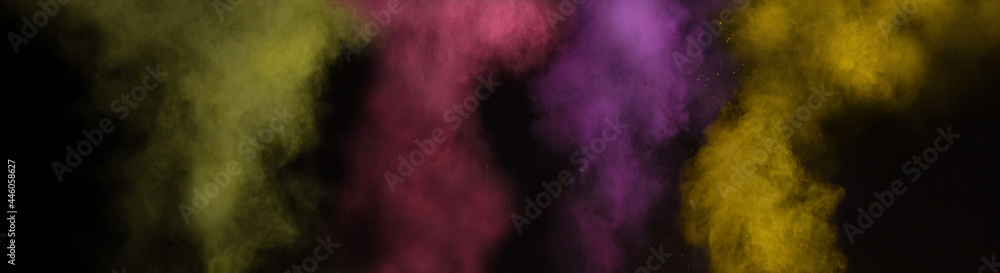 Beautiful explosive background of holi powders with yellow magenta violet and green colors flying over a black background