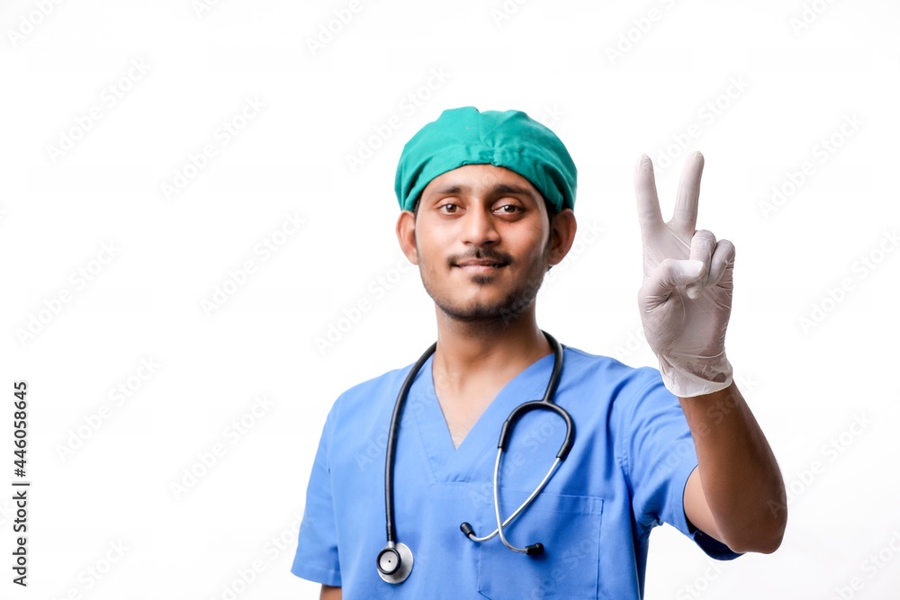 Young indian doctor showing victory sign over white background. Young indian doctor showing victory sign over white background.
