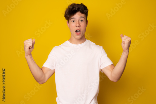 Lucky young man isolated over yellow background