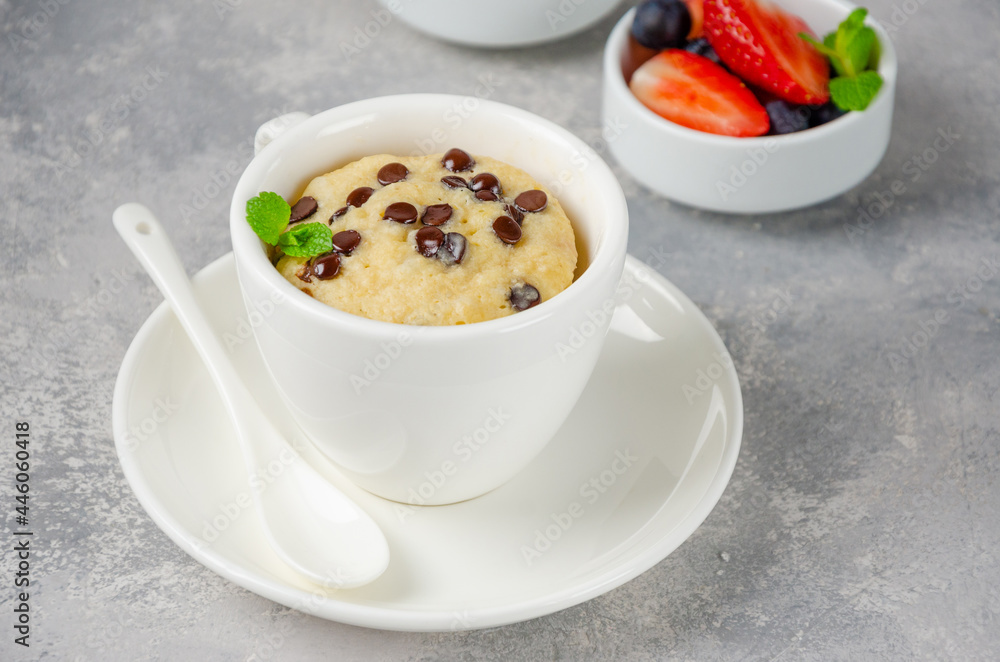 Mug cake with chocolate chips, fresh berries and cream on a gray concrete background. Copy space. Mug cake with chocolate chips, fresh berries and cream on a gray concrete background. Copy space.