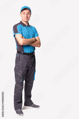 On time delivery service. Young logistic bearded man in blue uniform standing with folded hands and smiling.