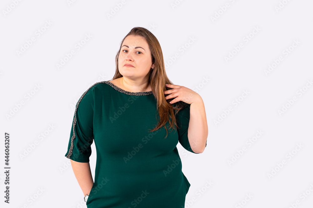 Meditative blonde woman plus size in green dress posing on camera touching her long hair looking ahead. Meditative blonde woman plus size in green dress posing on camera touching her long hair looking ahead.